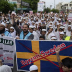 Muslim protesters hold copies of the book 'Quran' as they chant slogans to denounce the burning of the Islamic holy book 'Quran' that took place in Sweden, in Lahore, Pakistan, Sunday, July 9, 2023. švedska sweden quran kuran paljenje